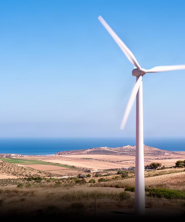 Aerogenerador moderno girando sobre un campo costero de Andalucía bajo un cielo despejado